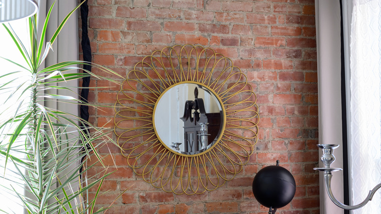 A sunburst mirror on brick wall