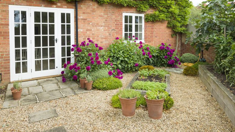 Brick house with backyard rock landscaping and blooming shrubs.