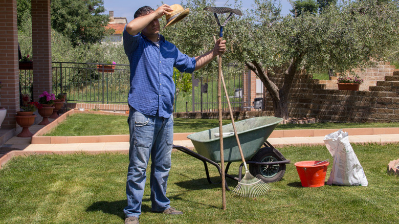 Man wiping sweat from his brow while doing yard work