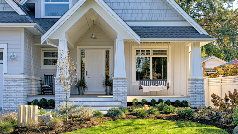 A traditional home with a front porch swing and rocking chairs