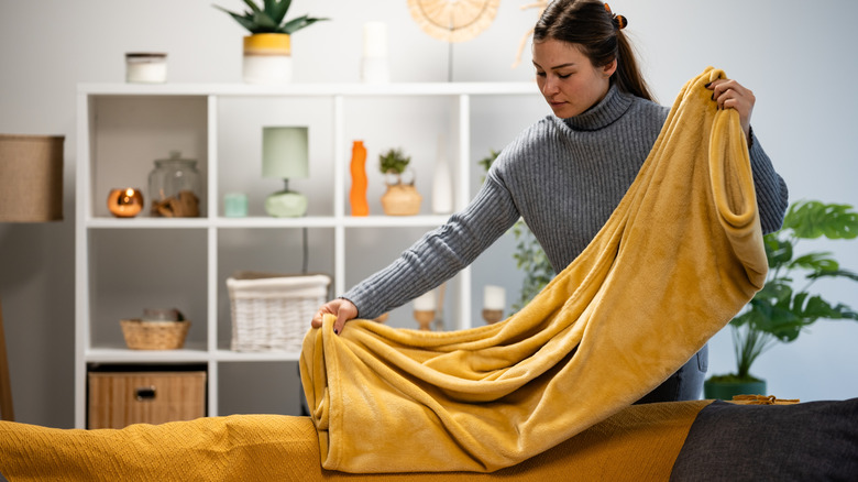 woman folding blanket on couch