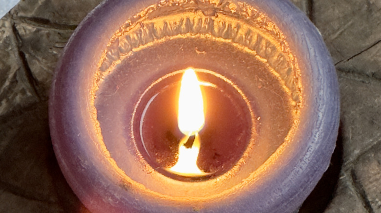 Closeup of a burning candle with melted candlewax in the center