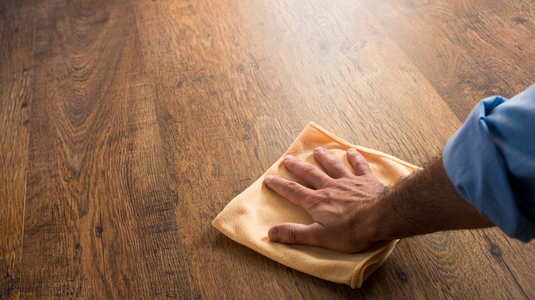 Close-up of a man buffing a hardwood floor with a microfiber cloth