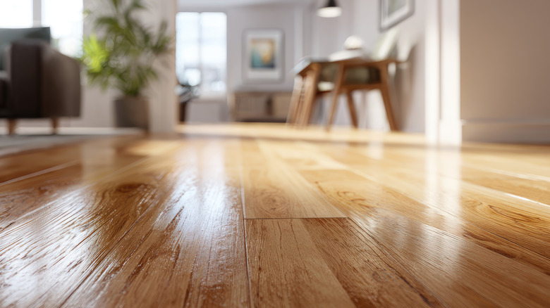 Close-up of a shiny hardwood floor with a blurred living room in the background