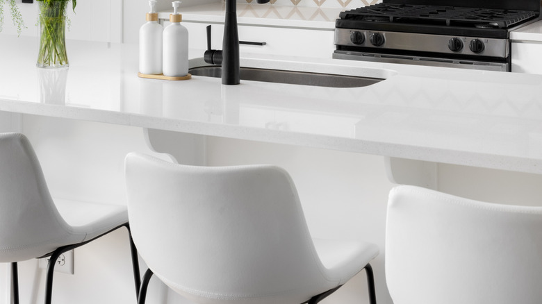 A modern black and white kitchen with glossy white bar stools.