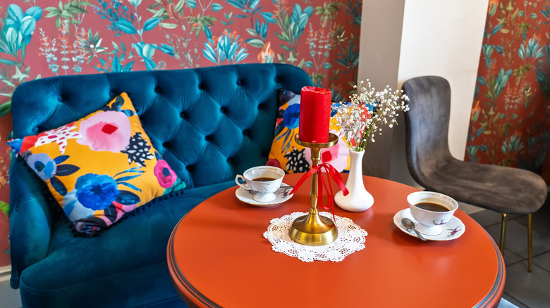eclectic space with bold red wallpaper, blue sofa and orange table