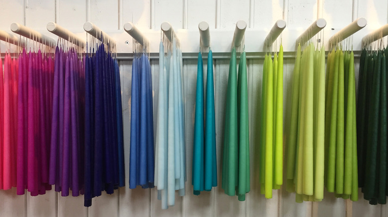 various colored taper candles hanging against white wall