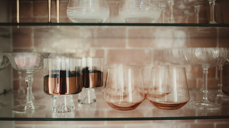 An assortment of wine glasses on display on glass shelves.