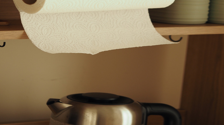 A paper towel rack that is hanging from a cabinet.