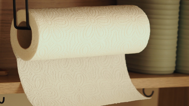 A paper towel rack that is hanging from a cabinet.