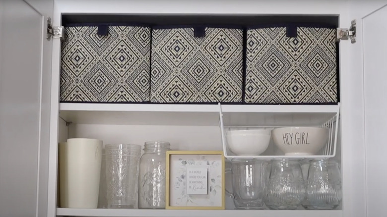 Open cabinet with collapsible storage boxes on the top shelf