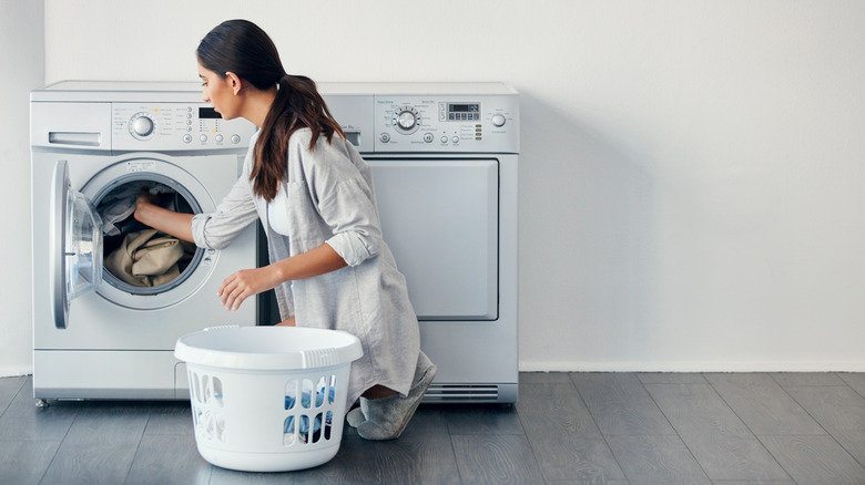 Woman kneeling on the floor taking clothes out of dryer