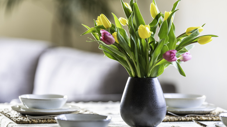 A vase of tulips is sitting on a dining table