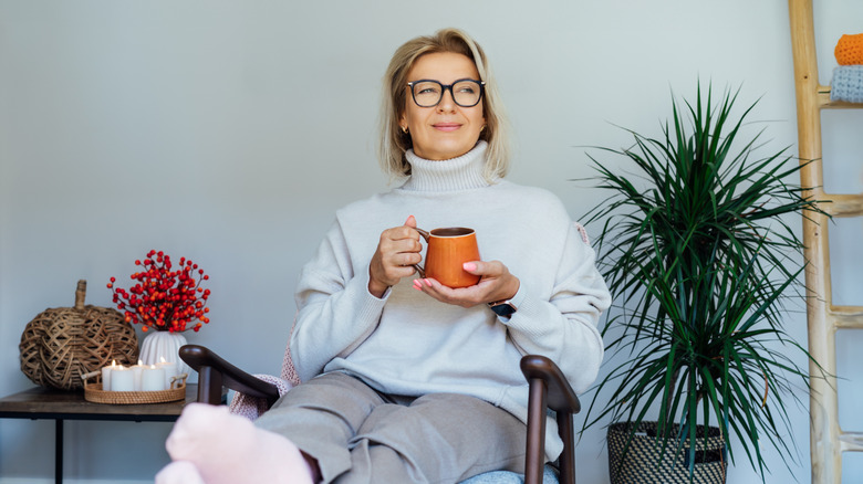 Woman sitting with mug surrounded by home décor