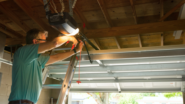 Homeowner installing something on his garage door motor.