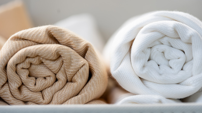 A close-up of white and beige rolled up linen towels.