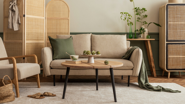 A wooden coffee table covered in decor in front of a two-seater couch