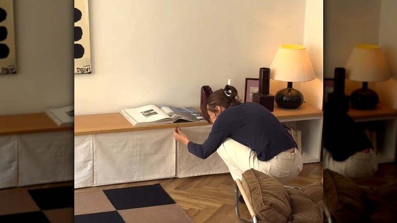 person covering front of BESTÅ stand with cut curtains