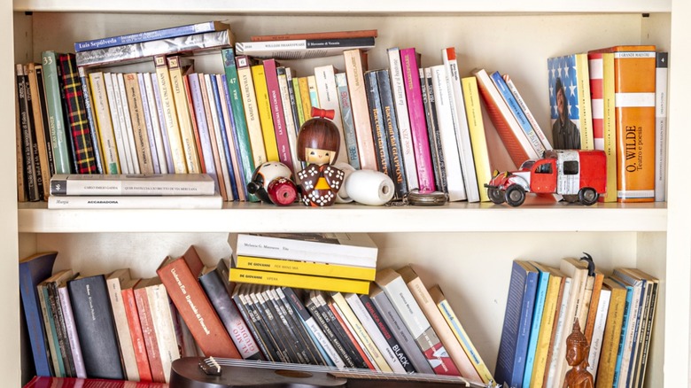 cluttered white bookshelves with books and children's toys