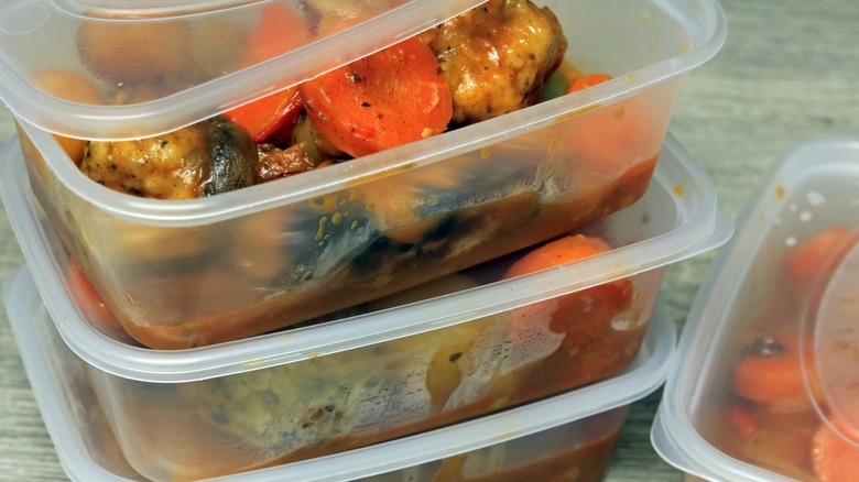 Meal prep in stacked plastic containers with vegetables and sauce