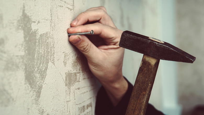 Hammering nail in plaster wall