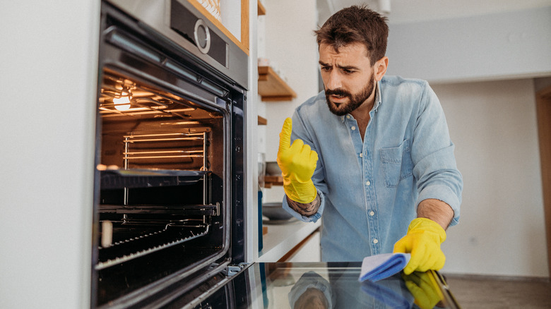 Man cleaning oven with gloves