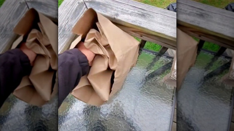 man stuffing brown paper bag into another brown paper bag to make fake wasp nest