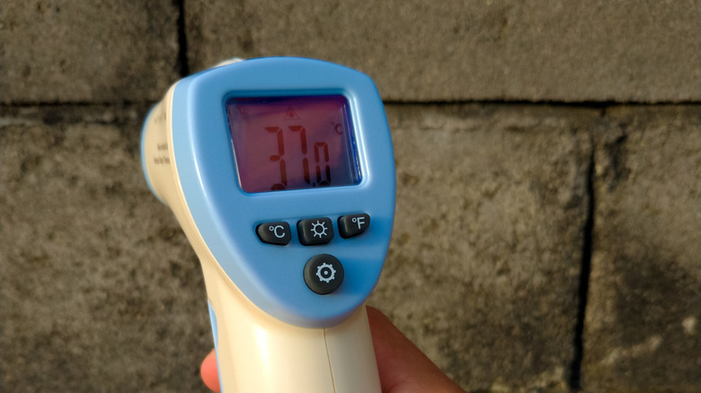 A person using an infrared camera on an exterior brick wall