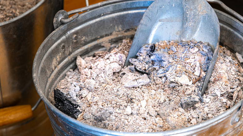 Wood ash in a metal bucket is ready to be scooped out