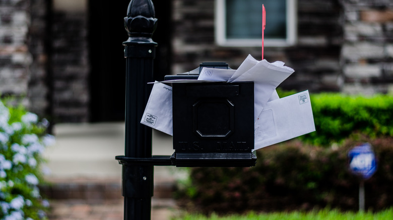 black mailbox overflowing with mail