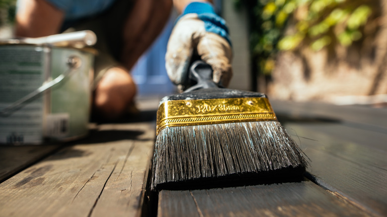 person painting wood deck black