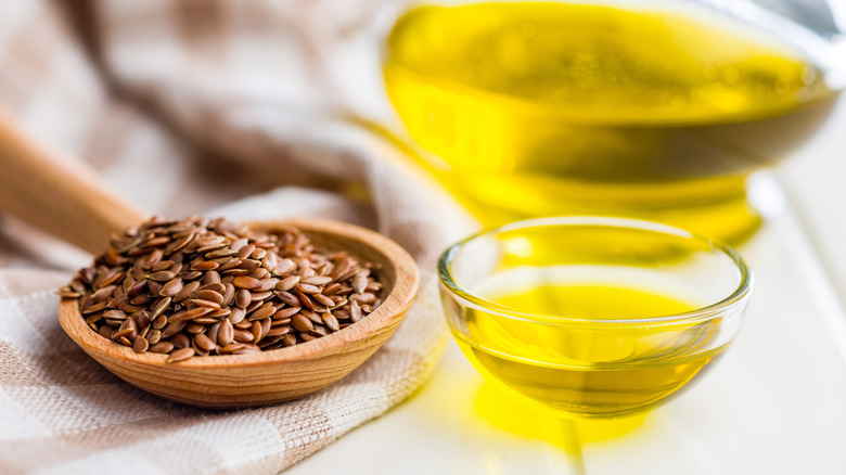 Linseed oil next to a bowl full of flax seeds.