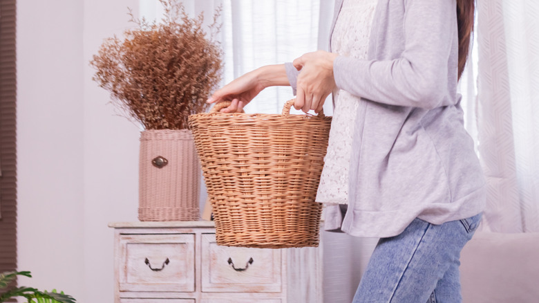 A woman carrying a large wicker basket with handles.