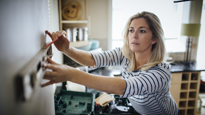 Woman carefully checking level on a wall