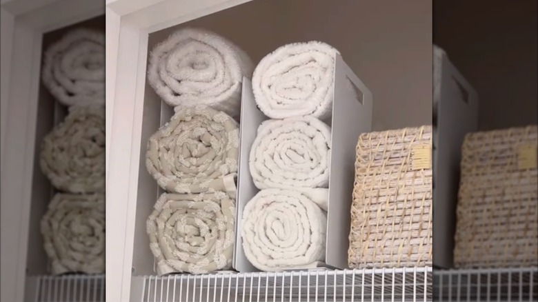 photo of six towels rolled up and placed on an organizer rack in a cabinet