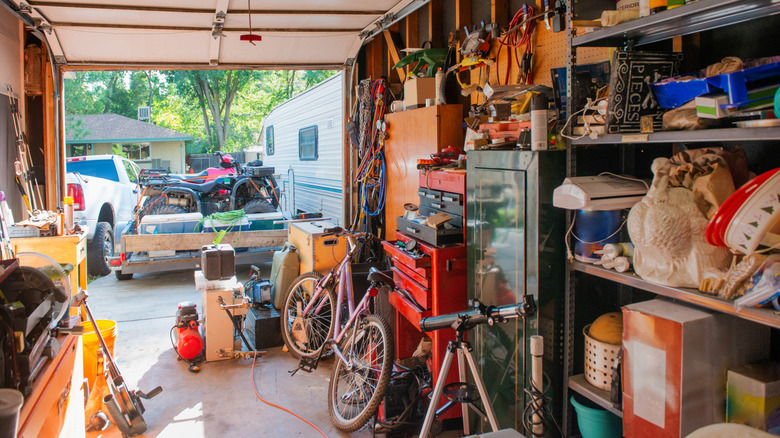 a cluttered garage with the door open
