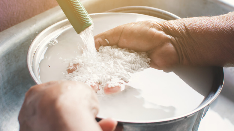 Hands rinsing rice in a pot sitting in a sink