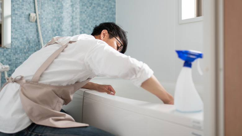 person kneeling and scrubbing a tub