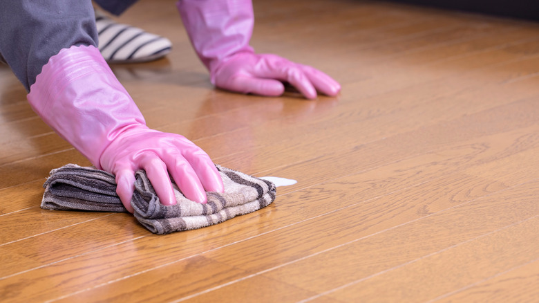 woman wiping hardwood floor with cleaning cloth