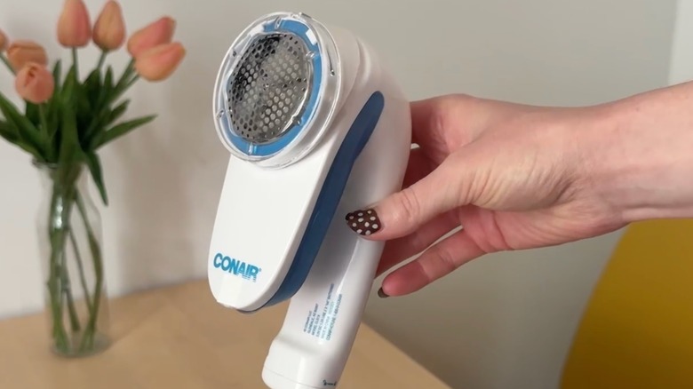 A hand holding a conair fabric defuzzer