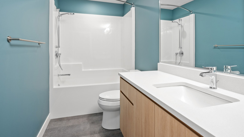 A simple bathroom with teal walls and white, ceramic fixtures