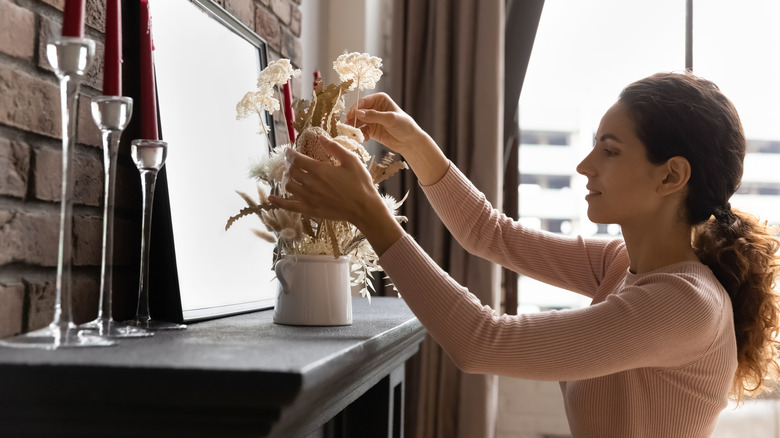 woman arranging flowers on mantel