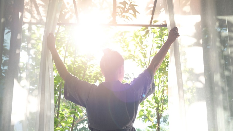 woman opening curtains