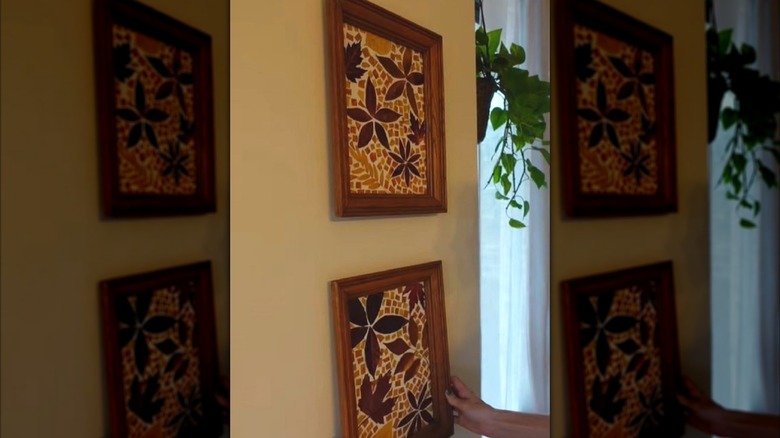 A person hanging wall art made from fall leaves