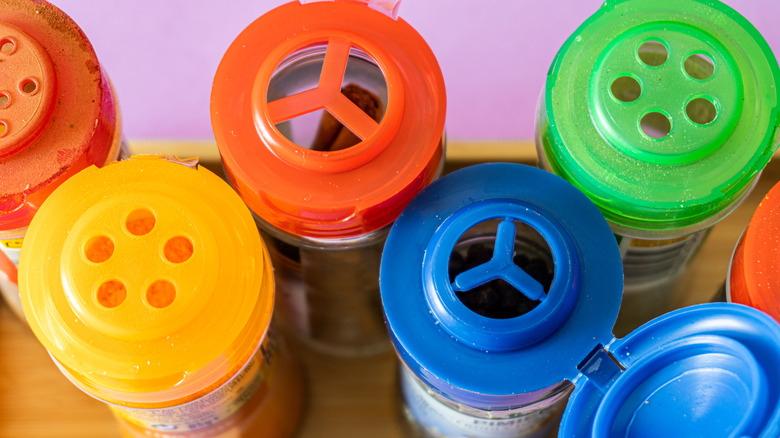 View of spice jars from above, each jar features a plastic lid in a different color (red, yellow, blue, green)