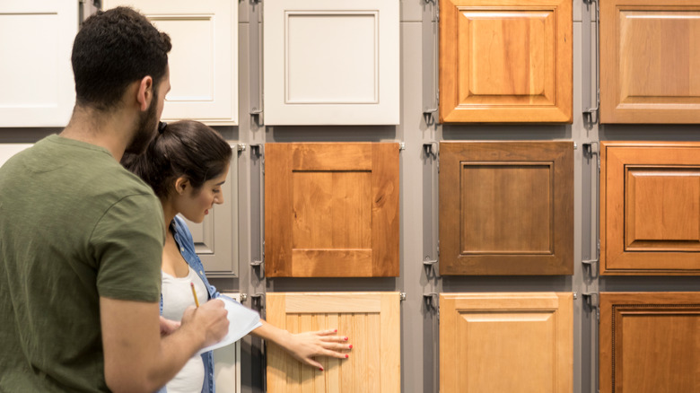 Two people look at kitchen cabinet samples in a store