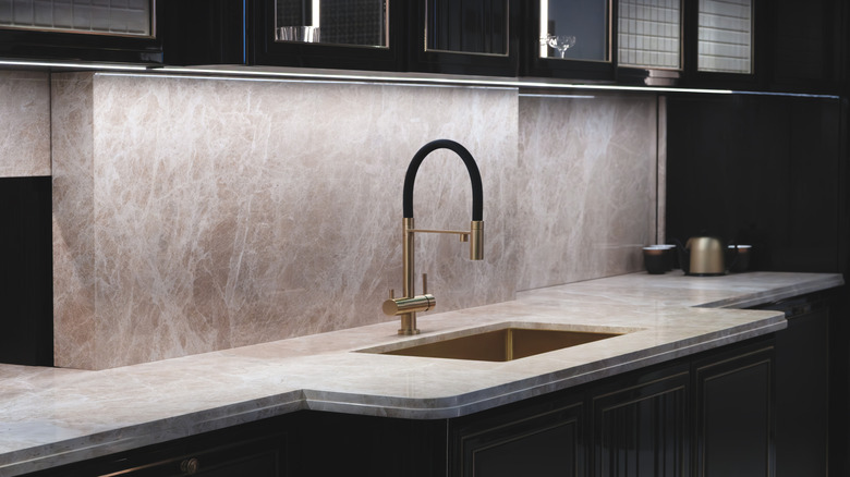 Kitchen sink with beige granite countertops and black cabinets