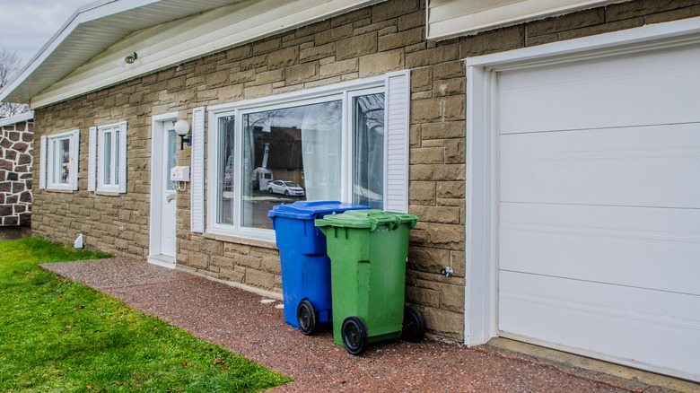 Blue and green garbage bins outside a property