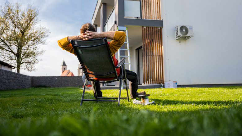 Man relaxing in chair in fenced yard.