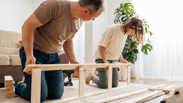 Two people assembling a wooden piece of furniture